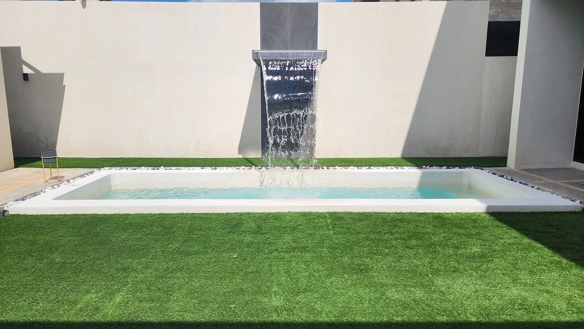 Piscina con muro de agua y patio con pasto sintético en Dzityá